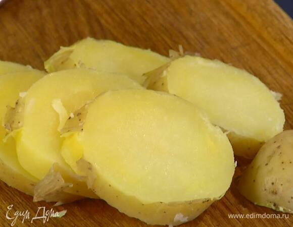 Картофель отварить в мундире практически до готовности, затем, не очищая, нарезать поперек кружками.