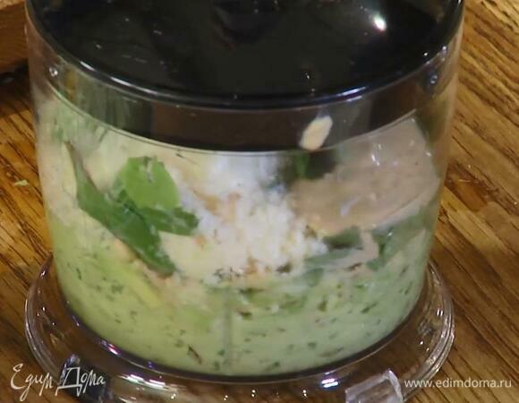 Кедровые орехи, руколу, веточки базилика и очищенный чеснок поместить в чашу блендера, добавить авокадо, половину натертого сыра, 2 ст. ложки оливкового масла, и пасту тахини, выжать сок из половинки лимона и все взбить.