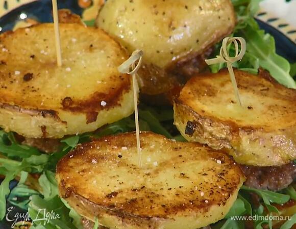 Руколу выложить на тарелку, сверху поместить котлетки, накрыть их обжаренным картофелем и скрепить шпажками.