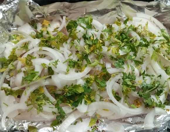 Нарезать лук полукольцами, выложить на рыбу. Посыпать зеленью. Накрыть форму фольгой.