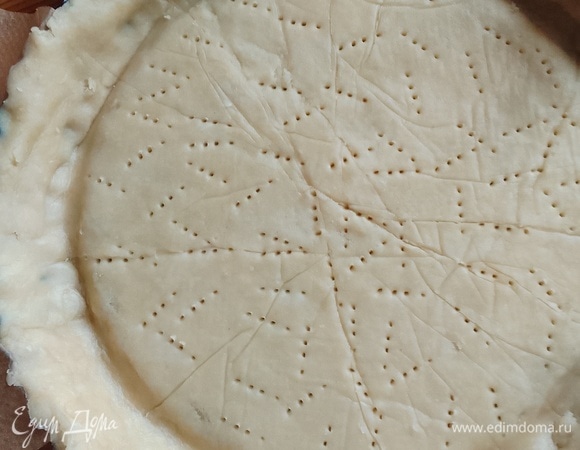 Вынуть тесто из холодильника. Раскатать между двумя листами пергамента. Аккуратно снимите верхний лист пергамента. На тесто положите полоски пергамента крест-накрест, эти полоски должны быть немного длиннее размера формы. Они помогут после приготовления вынуть тарт из неразъемной формы. Накройте тесто перевернутой формой, подложите руки под пергамент с тестом и переверните. Снимите пергамент. Выровняйте края теста в форме, удалите лишнее тесто с ободка формы. Наколите тесто (дно) вилкой. Уберите форму с тестом в холодильник на 30 минут.