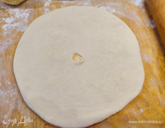 Перевернуть шарик швом вниз и аккуратно раскатывать в тонкую лепешку. Лучше делать это руками. Можно и скалкой, но не сильно нажимать. В готовом пироге в середине сделать дырочку.