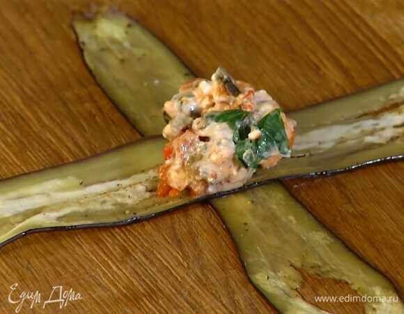 Две полоски запеченного баклажана уложить друг на друга крестиком, в центр поместить начинку и свернуть в конвертик.