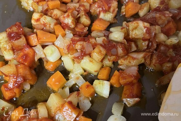 На среднем огне разогреть сковороду с растительным маслом. Добавить нарезанные лук, чеснок, морковь, картофель, кабачок и, помешивая, обжаривать 7–8 минут. Добавить в сковороду томатную пасту. Помешивая, обжаривать еще 1 минуту.