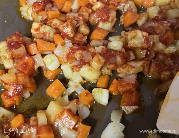 На среднем огне разогреть сковороду с растительным маслом. Добавить нарезанные лук, чеснок, морковь, картофель, кабачок и, помешивая, обжаривать 7–8 минут. Добавить в сковороду томатную пасту. Помешивая, обжаривать еще 1 минуту.