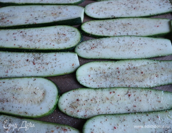 Смазать кисточкой оливковым маслом с двух сторон пластины цукини, поместить на противень, посыпать итальянскими травами, солью.