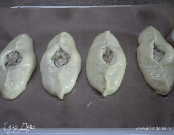Подошедшее тесто разделить на 10 кусочков. Каждый раскатать в овальную лепешку, в середину выложить по полной столовой ложке начинки и придать характерную для расстегаев форму лодочки с отверстием.