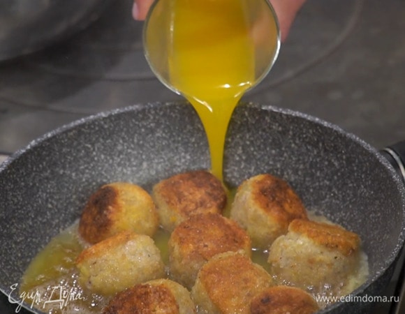 Разогреть в глубокой сковороде 2 ст. ложки оливкового масла и обжарить фрикадельки со всех сторон до золотистой корочки, затем влить апельсиновый сок, кленовый сироп и уксус, накрыть крышкой и оставить томиться.