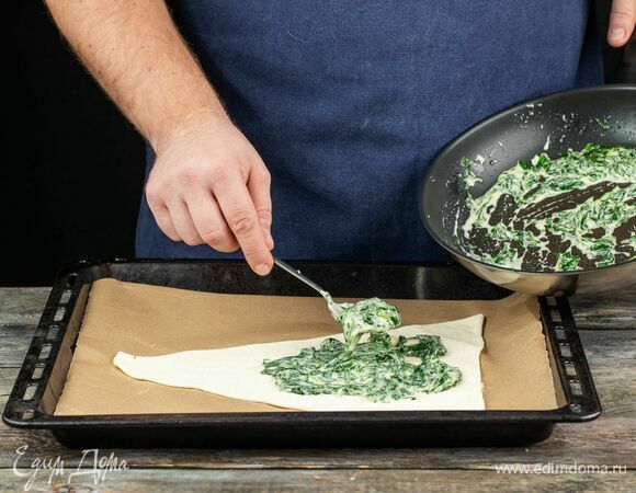 Раскатайте тесто, вырежьте 2 треугольника. Подготовьте противень, застеленный пергаментной бумагой. Выложите на бумагу первый треугольник, распределите по нему начинку.