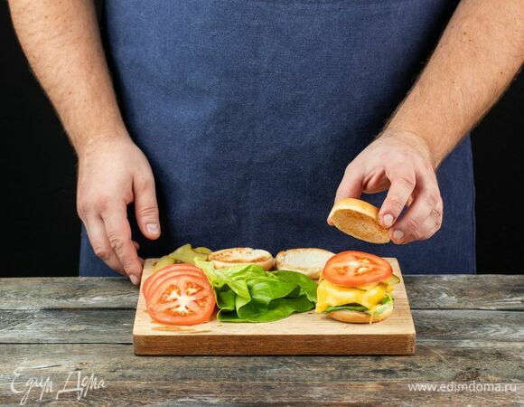 На основание выложите лист салата, котлету с расплавленным на ней сыром, огурец и помидор. Накройте второй булочкой и повторите то же самое с остальными заготовками.