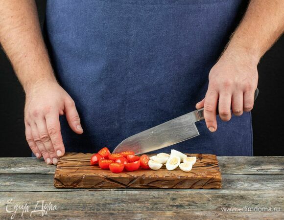 Отварите перепелиные яйца. Остудите, очистите и разделите на половинки. Помидоры черри также разрежьте пополам.