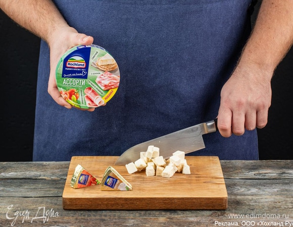 Произвольно нарежьте 4 треугольника плавленого сыра «Зеленое ассорти». Для этой закуски советуем использовать сыр с ароматной зеленью и томатами, а также треугольники со сливочным вкусом. Если вместо лосося взять обжаренное куриное филе, дополнить его лучше сыром с деликатесной ветчиной по-итальянски и треугольниками с беконом.