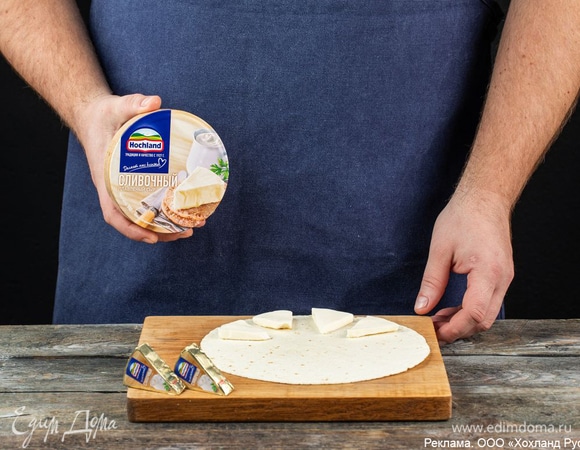 Разделите треугольники плавленого сыра Hochland «Сливочный» пополам по узкой стороне. Вам необходимо сохранить изначальную форму кусочков. Положите четыре половинки Hochland «Сливочный» на тортилью.