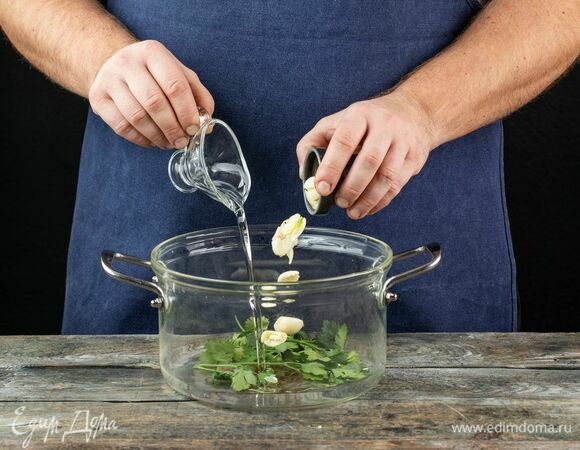 В разогретую кастрюлю налейте оливковое масло, добавьте зубчики чеснока, раздавленные ножом, и пучок петрушки.