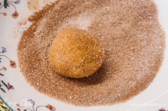 Из охлажденного теста сформировать шарики (примерно по 42 грамма) и обвалять их в смеси белого сахара и корицы.