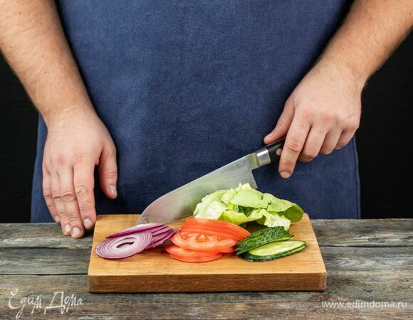 Подготовьте ингредиенты для бургера: тонко нарежьте свежие огурцы, помидоры и красный лук. Помойте и обсушите листья салата.