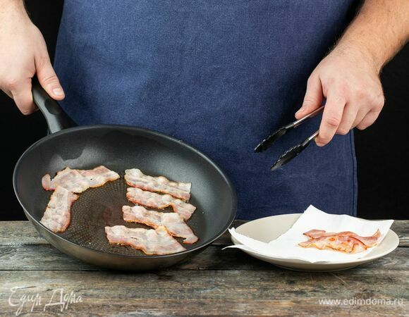 Обжарьте бекон на сухой сковороде, выложите на бумажное полотенце, чтобы оно впитало лишний жир.