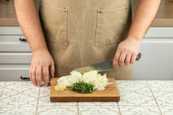 Нашинкуйте капусту, нарежьте лук тонкими кольцами, чеснок и зелень измельчите произвольно.