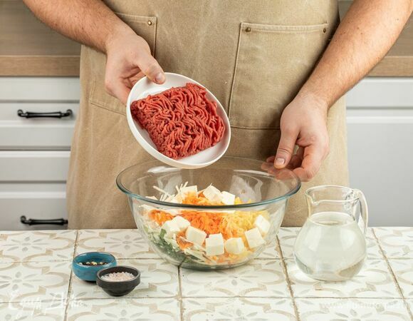 Смешайте овощи с сыром, зеленью и фаршем, приправьте начинку солью и перцем. Влейте воду.