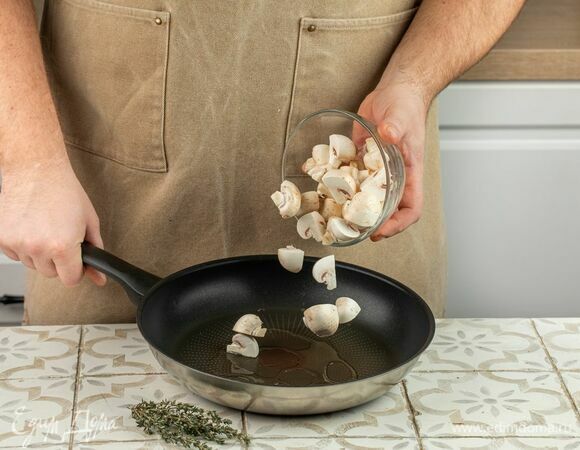 В это время нарежьте шампиньоны на слайсы, обжарьте их на сковороде с добавлением небольшого количества растительного масла. Чтобы получить интересный аромат, добавьте к маслу веточку тимьяна.
