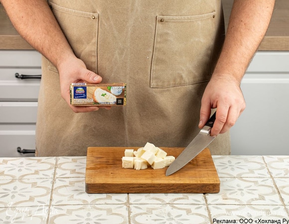 Нарежьте плавленый сыр Hochland «Сливочный» на кубики. Он придаст запеканке а-ля бешбармак сочность, нежный сливочный вкус, соединит рассыпчатое мясо и кусочки овощей.