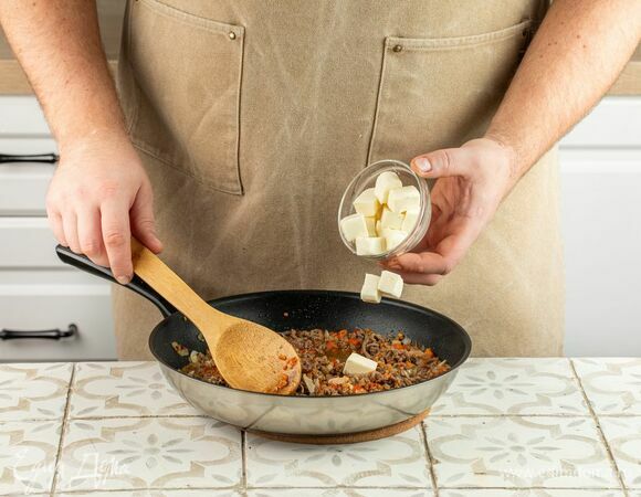 Смешайте половину сыра с обжаренным фаршем и овощами, вторую половину отложите.