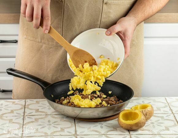 Когда картофель будет готов, раскройте фольгу и разрежьте клубни вдоль, не доходя до конца. Аккуратно удалите часть мякоти, оставив плотные стенки по бокам. Соедините картофельную мякоть и подготовленную заправку.