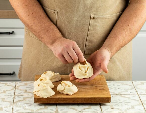 Тесто разделите на части и раскатайте круги. В центр каждого выложите начинку и соедините уголки в форме мантов.