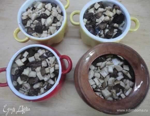 Затем выложите яблочно-луковую смесь. Влейте по 1 ст. л. масла и по полстакана кипящей воды или грибного бульона. Накройте горшочки крышками и поставьте в холодную духовку. Включите духовку на 180°C. Готовьте 1 час.