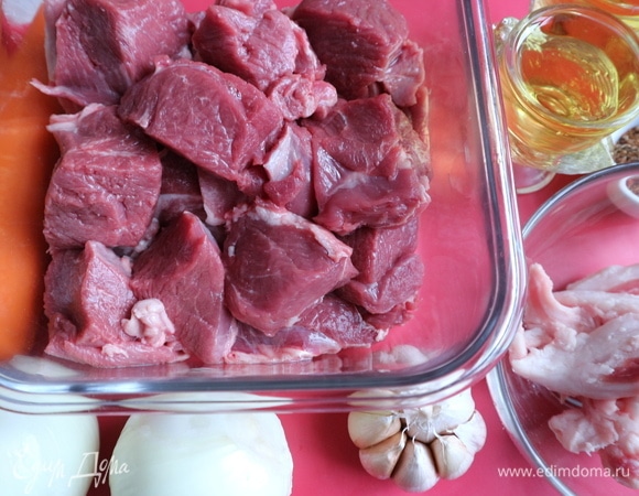 Баранину (у меня здесь бараний окорок) нарезать на кусочки среднего размера, посолить частью соли от указанного в ингредиентах количества, поперчить. Теплоемкую кастрюлю с толстым дном (казан) разогреть на огне, положить кусочки бараньего сала, вытопить жир, шкварки выбросить. Добавить растительное масло, разогреть его до «точки кипения капли воды».