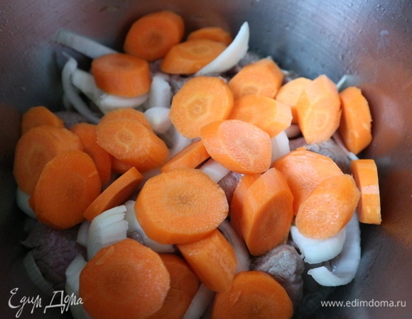 Добавить морковь, часть специй. Головку чеснока положить в центр. Закрыть крышкой. Крышка должна плотно закрывать кастрюлю (казан). Убавить огонь.