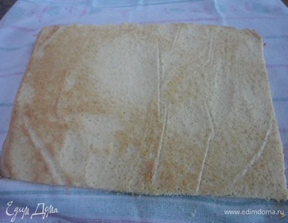 Распределяем его равномерно по всей поверхности с помощью лопатки. Выпекаем 10–12 минут до золотистого цвета при температуре 180°C. Не давая бисквиту остыть, перекладываем его на полотенце, обрезаем края. С помощью полотенца сворачиваем бисквит в рулет так, чтобы ровная сторона оказалась снаружи. Накрываем свернутый бисквит полотенцем и даем полностью остыть.