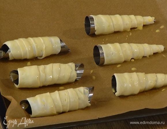 Желток перемешать с молоком, смазать трубочки и выложить их на противень, выстеленный бумагой для выпечки.