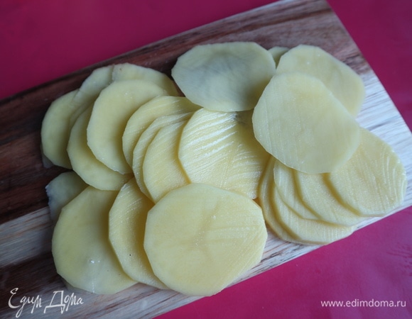 По центральной части в несколько рядов полосой от короткой стороны теста к противоположной, отступив от края, выложить нарезанный на очень тонкие кружочки картофель.