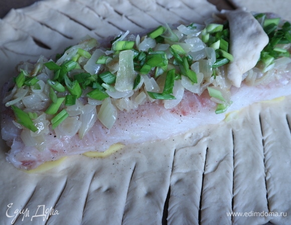 На тесте сделать диагональные разрезы ножом, не доходя до зоны начинки примерно на 1–1,5 см. Расположить полоски теста сверху начинки встречно, «косичкой», оставив небольшие промежутки в некоторых местах, чтобы дать выход пару при выпекании. Дать постоять минут 5.