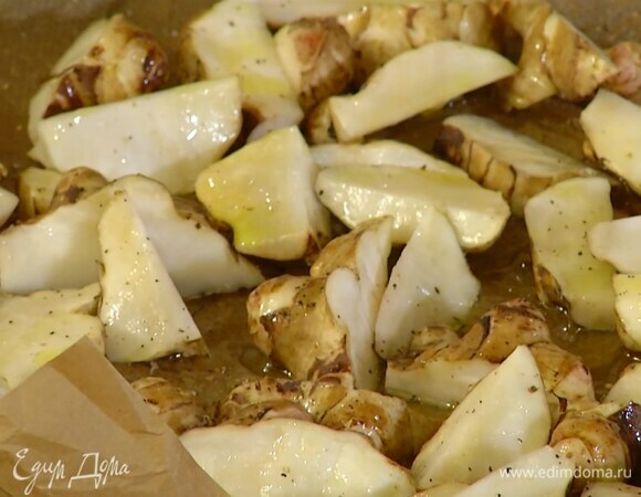 Топинамбур нарезать небольшими дольками, выложить в выстеленную бумагой для выпечки форму, слегка посолить и поперчить, полить 1 ст. ложкой оливкового масла и соком, выжатым из одного кружка апельсина.