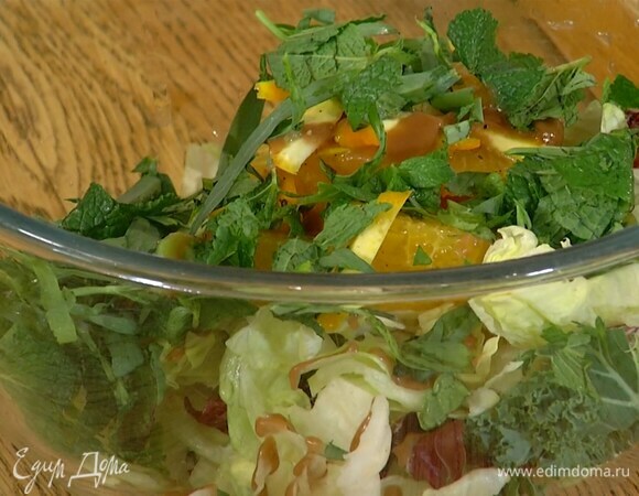 Салатные листья и нарезанный апельсин выложить в глубокую миску, полить готовой салатной заправкой, посыпать измельченной зеленью, добавить запеченный топинамбур и все перемешать.