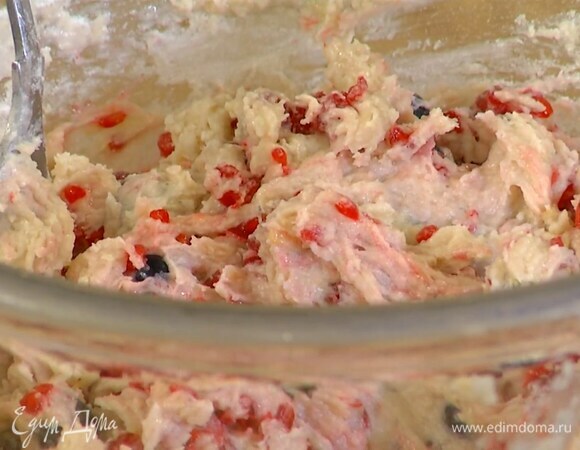 К йогурту влить ванильный экстракт, добавить лимонную цедру, взбитое масло с сахаром и все перемешать, затем всыпать муку с разрыхлителем, по 2 горсти голубики и малины и вымешать тесто.