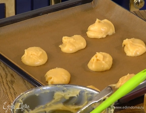 Противень застелить бумагой для выпечки и выкладывать смоченной в воде столовой ложкой шарики из теста на небольшом расстоянии друг от друга.