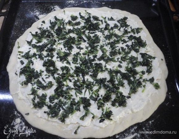 Сверху распределите подсоленный и поперченный по вкусу творожный сыр, отступая от краев пиццы. Равномерно разложите шпинат с чесноком.