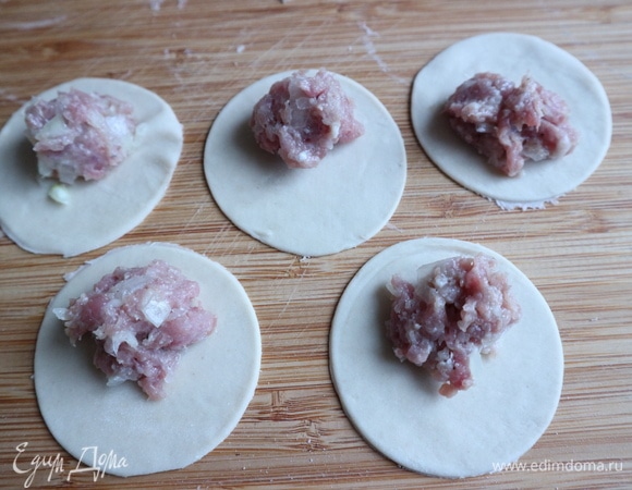 С помощью стакана (диаметр 7 см) сделать из теста кружочки, сначала штук 6–7, не больше, остальное раскатанное тесто оставить под кухонным полотенцем, чтобы не подсыхало. Положить начинку на каждый кружочек.