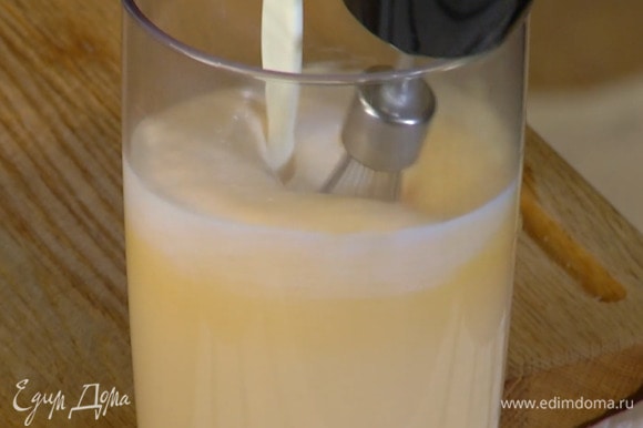 Яичные желтки и 150 г сахара взбить блендером с насадкой-венчиком на высокой скорости в пышную пену, затем, продолжая взбивать, тонкой струйкой влить сливочно-молочную смесь.