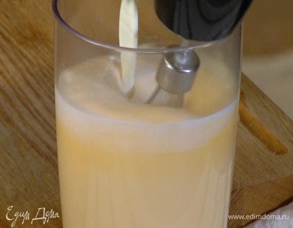 Яичные желтки и 150 г сахара взбить блендером с насадкой-венчиком на высокой скорости в пышную пену, затем, продолжая взбивать, тонкой струйкой влить сливочно-молочную смесь.