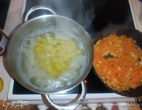 В кастрюлю с картошкой добавляем душистый перец горошком. В разогретой сковородке с растительным маслом обжариваем лук и морковь около 3 минут.