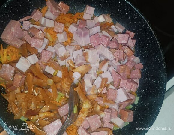 На сковородку добавляем копчености и чеснок. Обжариваем 5 минут. Это придаст зажарке и готовой солянке легкий копченый вкус и аромат.