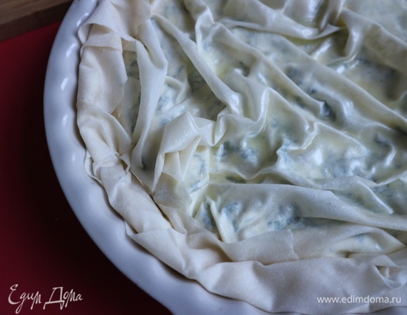 Положить третью часть начинки, накрыть листом фило (со складочками), смазать маслом, свисающие края теста подогнуть внутрь, чтобы внутри были небольшие бортики из теста, смазать их маслом.