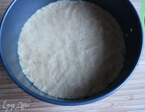 Поместить массу для основы чизкейка в разъемную форму, дно которой прикрыто бумагой для выпечки, а борта смазаны оливковым маслом. Примять массу руками или ложкой ко дну формы, чтобы масса размещалась равномерно. Убрать форму в холодильник.