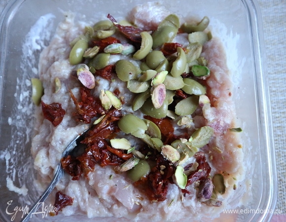 Затем добавить нарезанные зеленые оливки, нарезанные на половинки фисташки, перемешать.