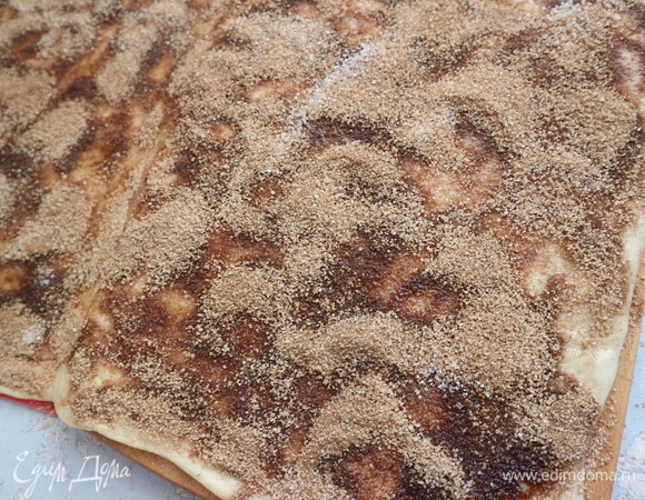 Потребуется растопленное (как у меня здесь) сливочное масло (75 грамм), можно использовать размягченное масло в том же количестве, выкладывая его как можно равномернее на тесто. Я пробовала и тот, и другой вариант. Смешать корицу с сахарным песком (195 грамм). Кисточкой нанести масло на поверхность, отступив от одного из длинных краев на 1,5 см. Таким же образом (отступив от одного из длинных краев) нанести равномерно корицу с сахарным песком.