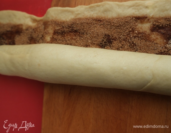 Скрутить рулет по длинной стороне (полоса без начинки остается наружной), стараясь немного прижимать тесто с начинкой.